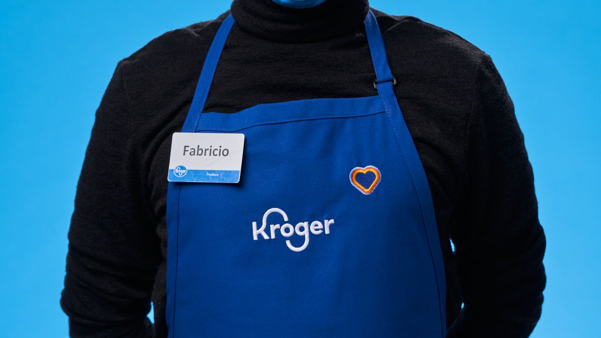 A Kroger associate wear the grocer's apron and heart logo.