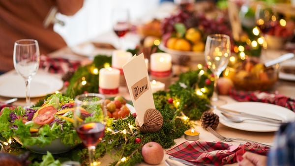 Close-up of a table set up for a holiday meal with red and black checkered napkins, a salad bowl and sparkling glasses.